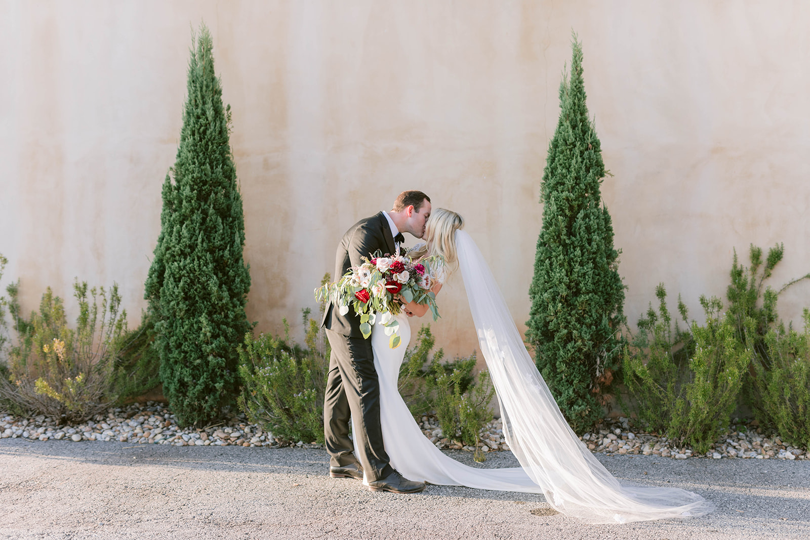 Bride and groom portrait with veil whilst bride holds a burgundy and blush garden style bouquet