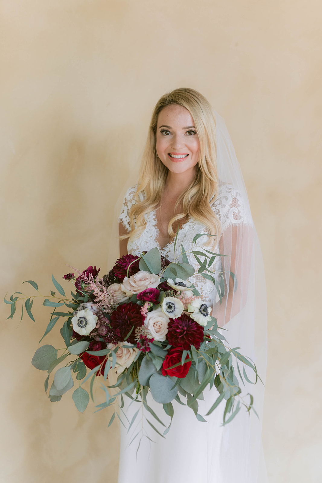 Bride holds a garden look bouquet featuring burgundy fall colors at her Montaluce Winery Wedding